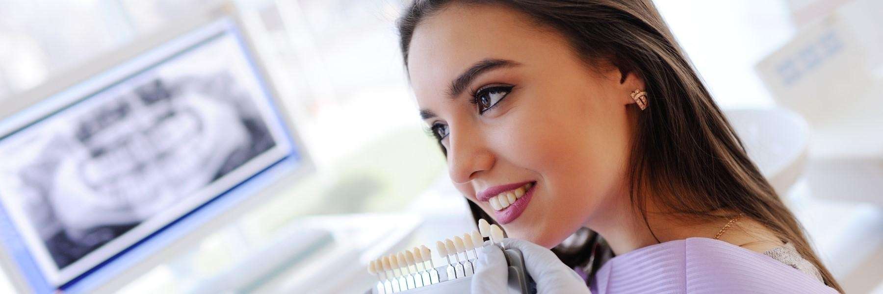 A woman and her dentist comparing tooth shades before teeth whitening | cosmetic dentistry