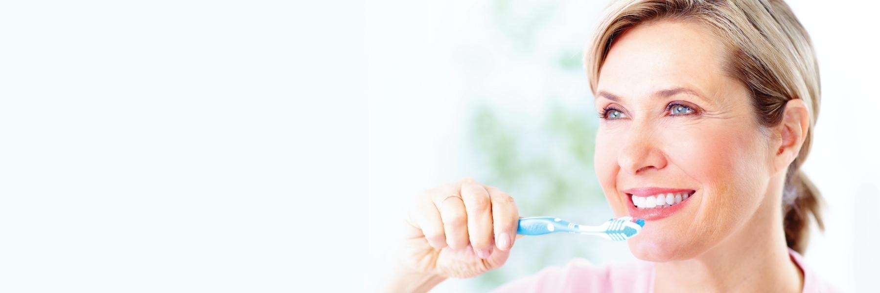A smiling woman brushing her teeth | dental care Charlestown