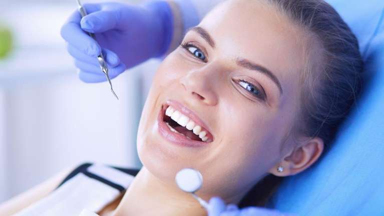 A smiling woman receiving a dental exam | dentist Charlestown NSW
