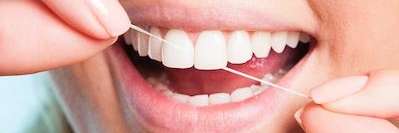 A woman flossing | dentist near me Charlestown